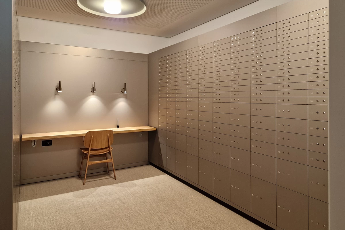 A secure room with many safe deposit boxes lining the wall.